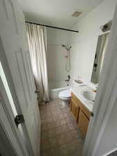 Full bathroom with visible vents, shower / bath combo with shower curtain, toilet, and vanity