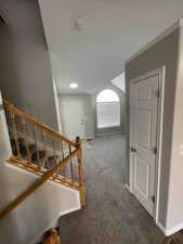 Stairs featuring vaulted ceiling, carpet flooring, and baseboards