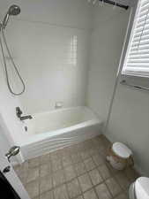 Full bathroom featuring baseboards, shower / tub combination, and toilet