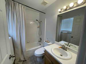 Full bath featuring vanity, visible vents, tile patterned flooring, shower / bath combination with curtain, and toilet