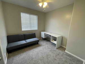 Living area featuring baseboards, carpet floors, and ceiling fan