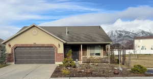 View of front of property featuring a mountain view, covered porch, concrete driveway, an attached garage, and brick siding