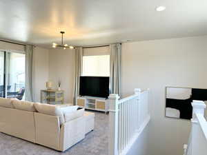 Upstairs Loft living area connect to upper covered deck with carpet flooring, recessed lighting, visible vents, and an inviting chandelier