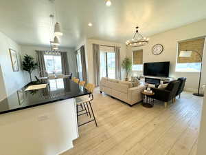 Living area with a chandelier, light wood-style flooring, baseboards, and a healthy amount of sunlight