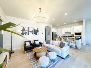 Living area with baseboards, recessed lighting, light wood-type flooring, and a chandelier