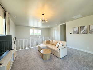Living room with a chandelier, carpet flooring, baseboards, and visible vents