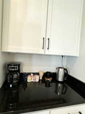 Coffee area details with white cabinetry and dark stone counters