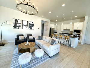 Living room featuring light wood-style flooring, recessed lighting, baseboards, and a chandelier