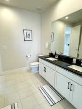 Bathroom connected to bedroom 3. Featuring tile patterned floors, toilet, baseboards, and a sink