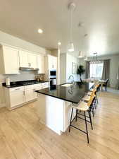 Kitchen with wall oven, built in microwave, under cabinet range hood, black gas stovetop, and a sink