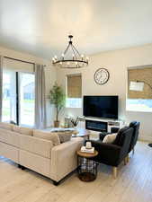 Living room with a chandelier, light wood-style flooring, and baseboards
