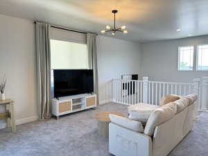 Carpeted living area with recessed lighting, baseboards, and a notable chandelier