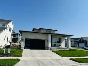 View of front of home with a porch, an attached garage, stone siding, and driveway