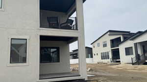 Rear view of house with a balcony and stucco siding