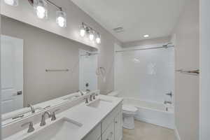 Bathroom featuring tile patterned flooring, washtub / shower combination, toilet, and a sink