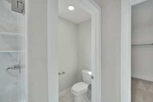 Full bath with walk in shower, toilet, and baseboards