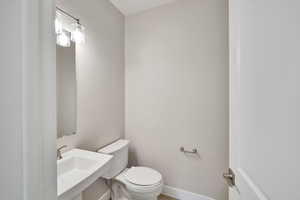 Half bathroom with a sink, baseboards, and toilet