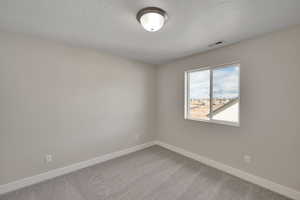 Spare room featuring carpet flooring, baseboards, and visible vents