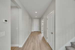 Hallway featuring recessed lighting, stairway, baseboards, and light wood-style flooring