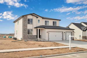 Traditional-style home featuring central air condition unit, an attached garage, driveway, and stucco siding