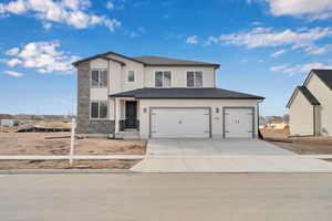 Traditional-style house featuring a garage, stone siding, concrete driveway, and stucco siding