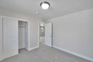 Unfurnished bedroom featuring light carpet, visible vents, a closet, and baseboards