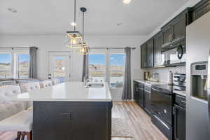 Kitchen featuring black appliances, a sink, a kitchen breakfast bar, tasteful backsplash, and light countertops