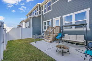 Rear view of property featuring a fenced backyard with grass that is maintained by HOA along with a good sized patio area