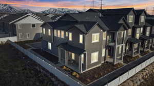 Property exterior at dusk with a mountain view, a fenced backyard, a residential view, a patio area, and board and batten siding