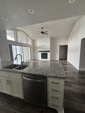 Kitchen featuring stainless steel dishwasher, light stone counters, open floor plan, and a sink