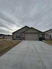 Single story home with stucco siding, a front lawn, a garage, and driveway