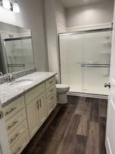Full bath with wood finished floors stall shower and vanity