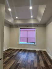 2nd master suite featuring a tray ceiling, baseboards, and wood finished floors
