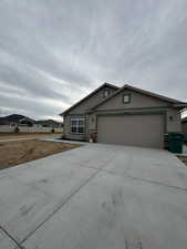 Single story patio home with stucco siding, a front lawn, a garage, and driveway
