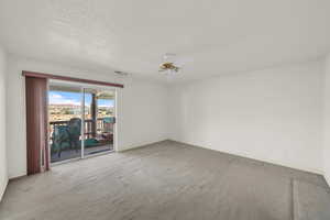 Empty room featuring visible vents, a ceiling fan, a textured ceiling, carpet flooring, and baseboards