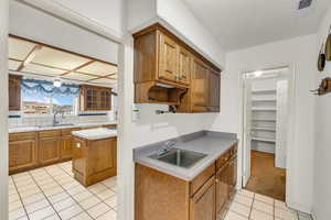 Kitchen featuring light tile patterned floors, visible vents, backsplash, and a sink