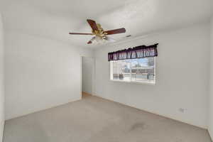 Carpeted spare room with a textured ceiling, baseboards, visible vents, and ceiling fan