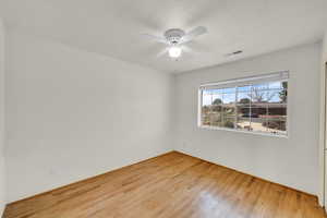 Spare room with visible vents, a textured ceiling, ceiling fan, and wood finished floors