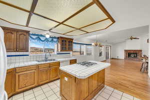 Kitchen featuring a sink, a center island, a fireplace, light tile patterned floors, and lofted ceiling