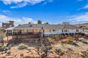 Rear view of property with stucco siding, a tile roof, and a deck