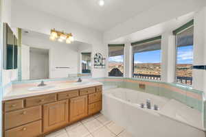 Full bathroom featuring a sink, a garden tub, double vanity, and tile patterned flooring