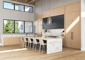 Kitchen with light wood finished floors, decorative backsplash, a healthy amount of sunlight, and light brown cabinets