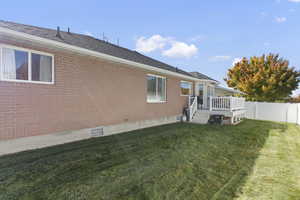 Rear view of property with a deck, brick siding, and a fenced backyard
