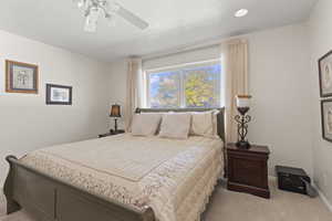 Bedroom with carpet, a ceiling fan, and a textured ceiling