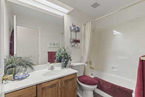 Bathroom with vanity, shower / bath combo with shower curtain, and a skylight