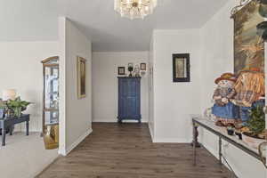 Hallway featuring wood finished floors and a chandelier