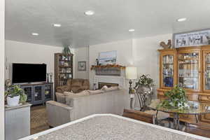 Living room featuring a textured ceiling, recessed lighting, a fireplace, and wood finished floors