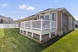 Back of house with brick siding, a lawn, and a wooden deck