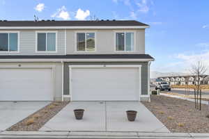 View of front of house with an attached garage, concrete driveway, and a shingled roof