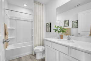 Bathroom featuring visible vents, shower / tub combo with curtain, toilet, wood finished floors, and vanity